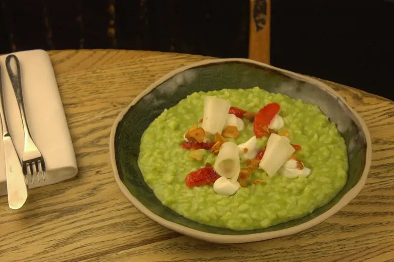 Pea risotto in a stoneware bowl on a wooden table