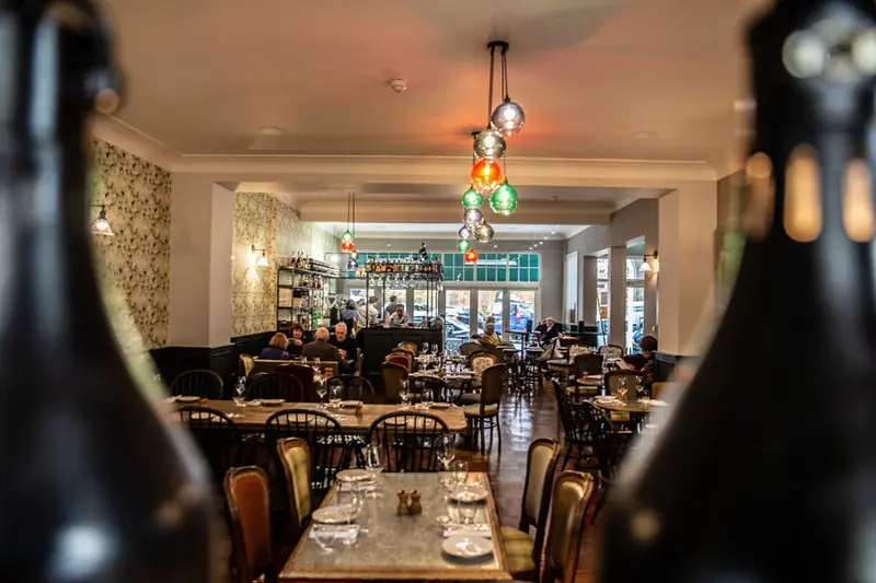 Restaurant tables framed by wine bottles
