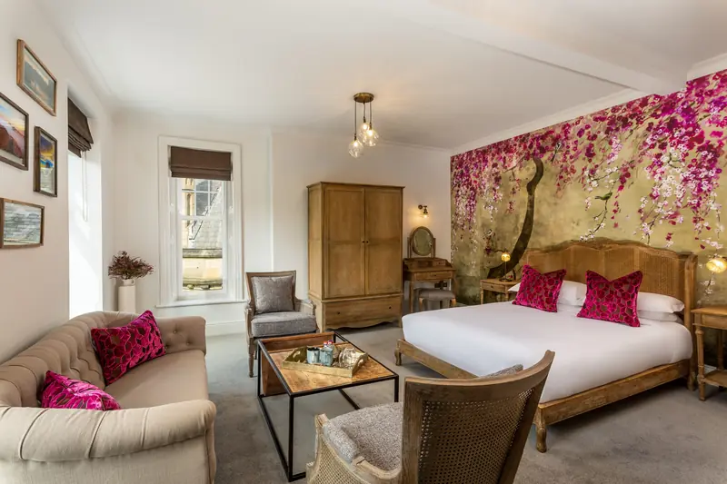 Superior bedroom with pink floral feature wall, king size bed and sofa