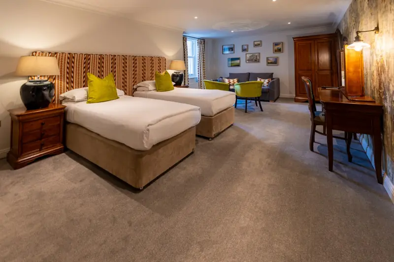 Twin bedroom with patterned wallpaper, two beds and a writing desk